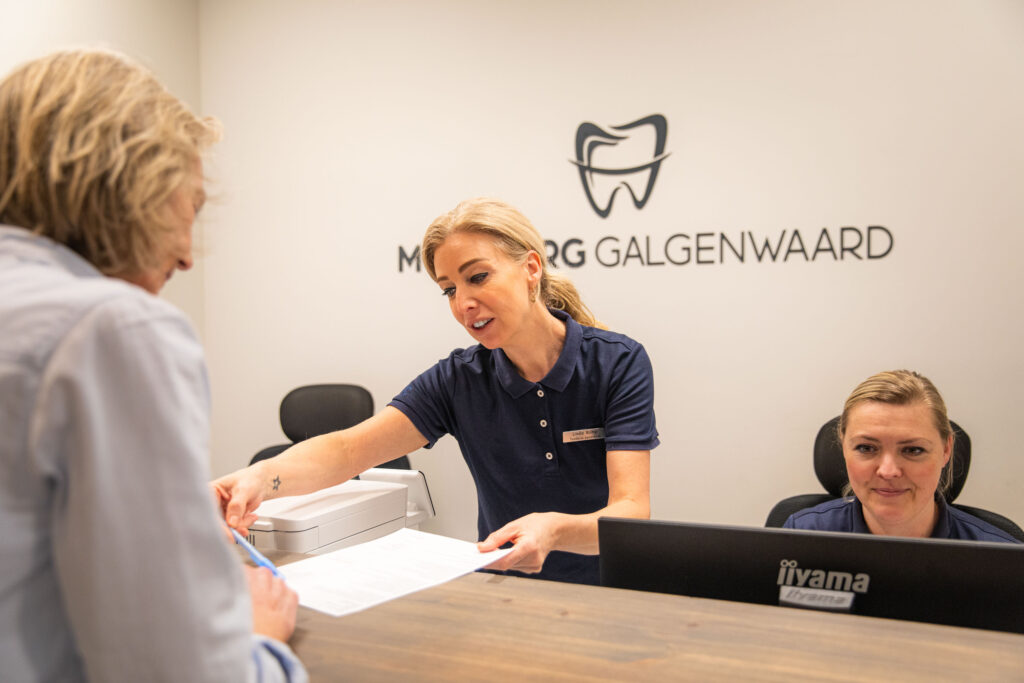 Een deskmedewerker die iets laat ondertekenen door een vrouw